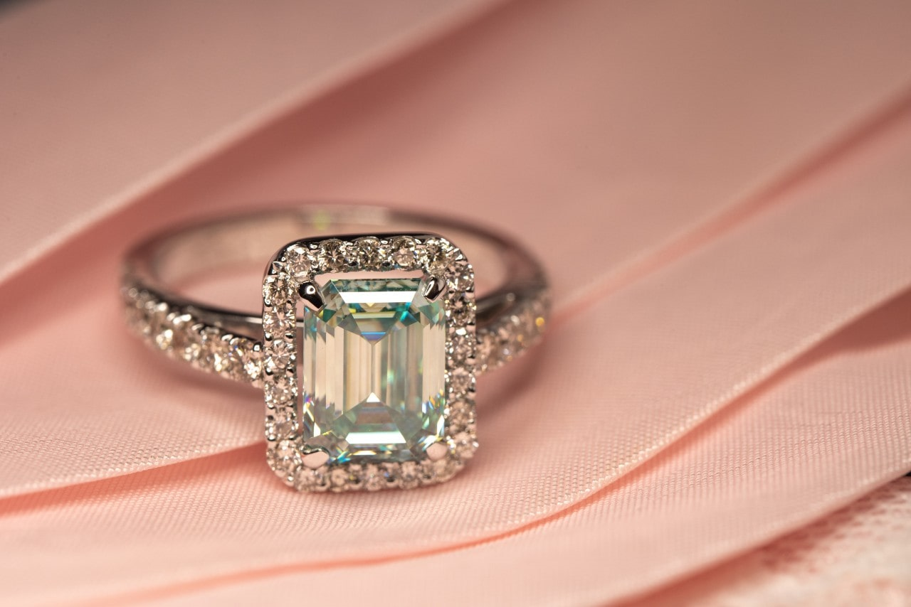 an emerald-cut engagement ring resting on a pink cloth