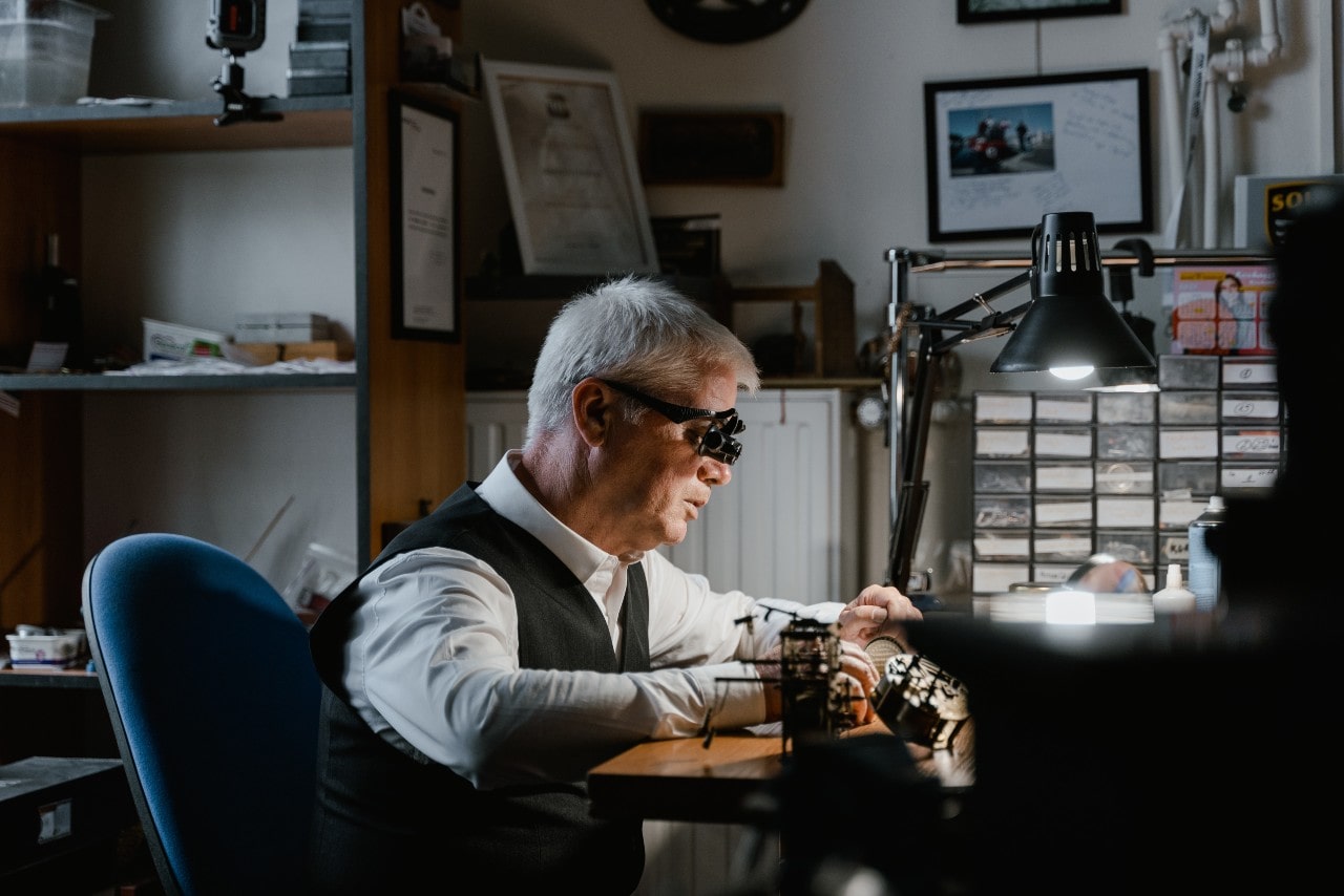 Watchmaker sitting at his workstation, deep into a renovation of a timepiece