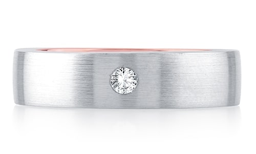 A white gold and rose gold wedding band with a single diamond accent.