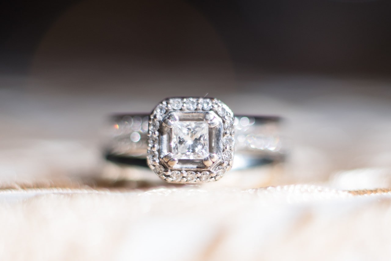 Engagement ring with a princess cut diamond center stone surrounded by a halo setting