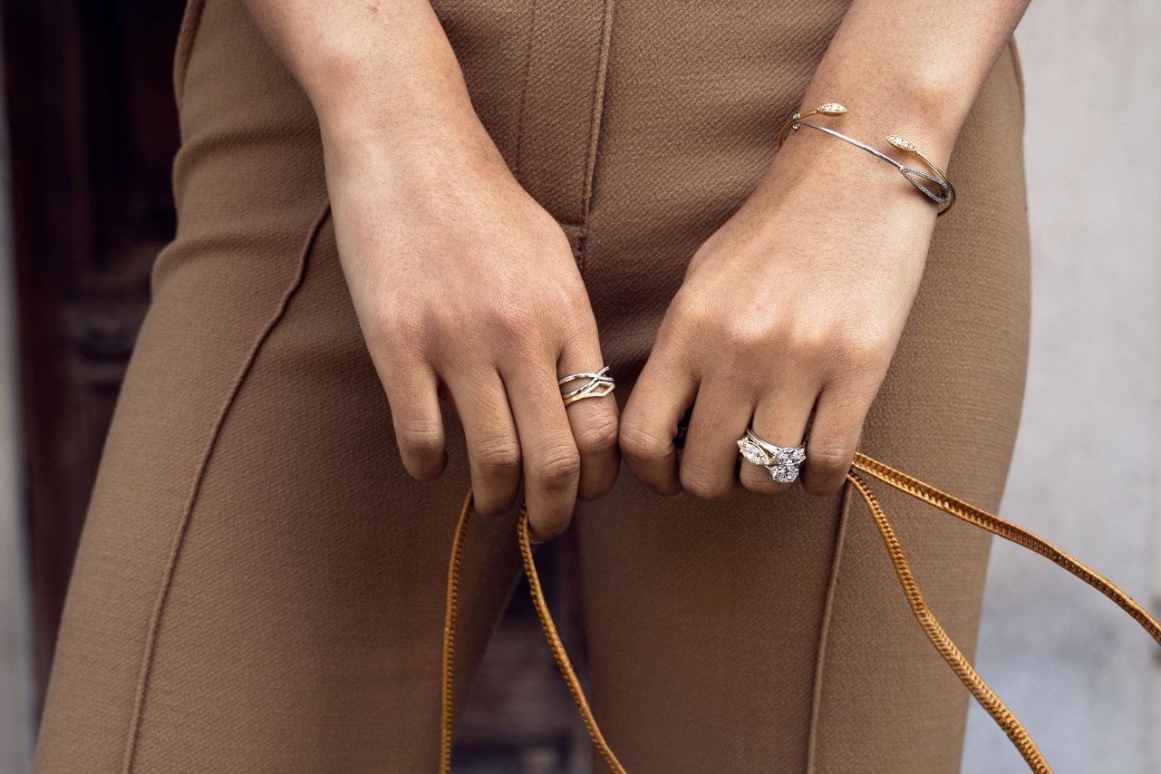Fancy lady holding a bag with a couple of dazzling TACORI fashion rings on her fingers