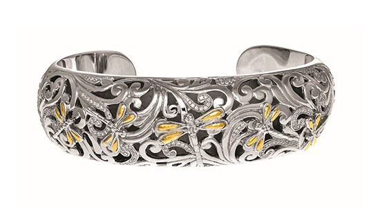 A thick, silver cuff bracelet with dragonfly motifs and gold details