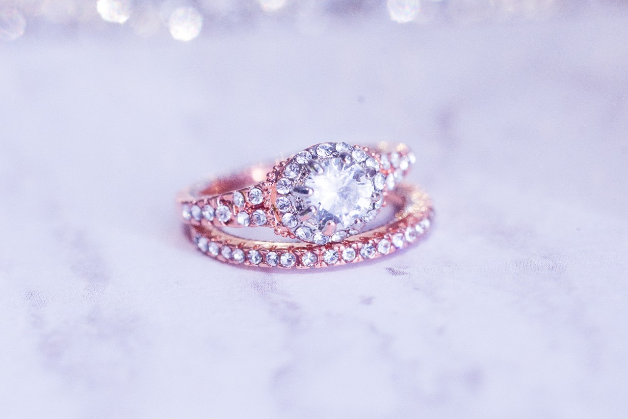 Rose gold engagement ring with diamond accents sitting on top of a matching wedding band
