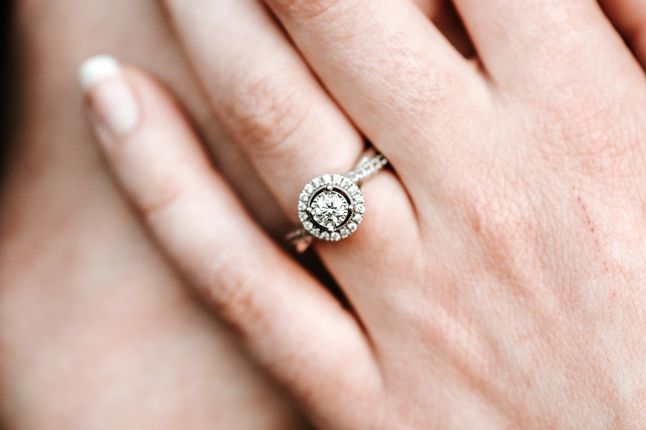 Hand with diamond halo engagement ring