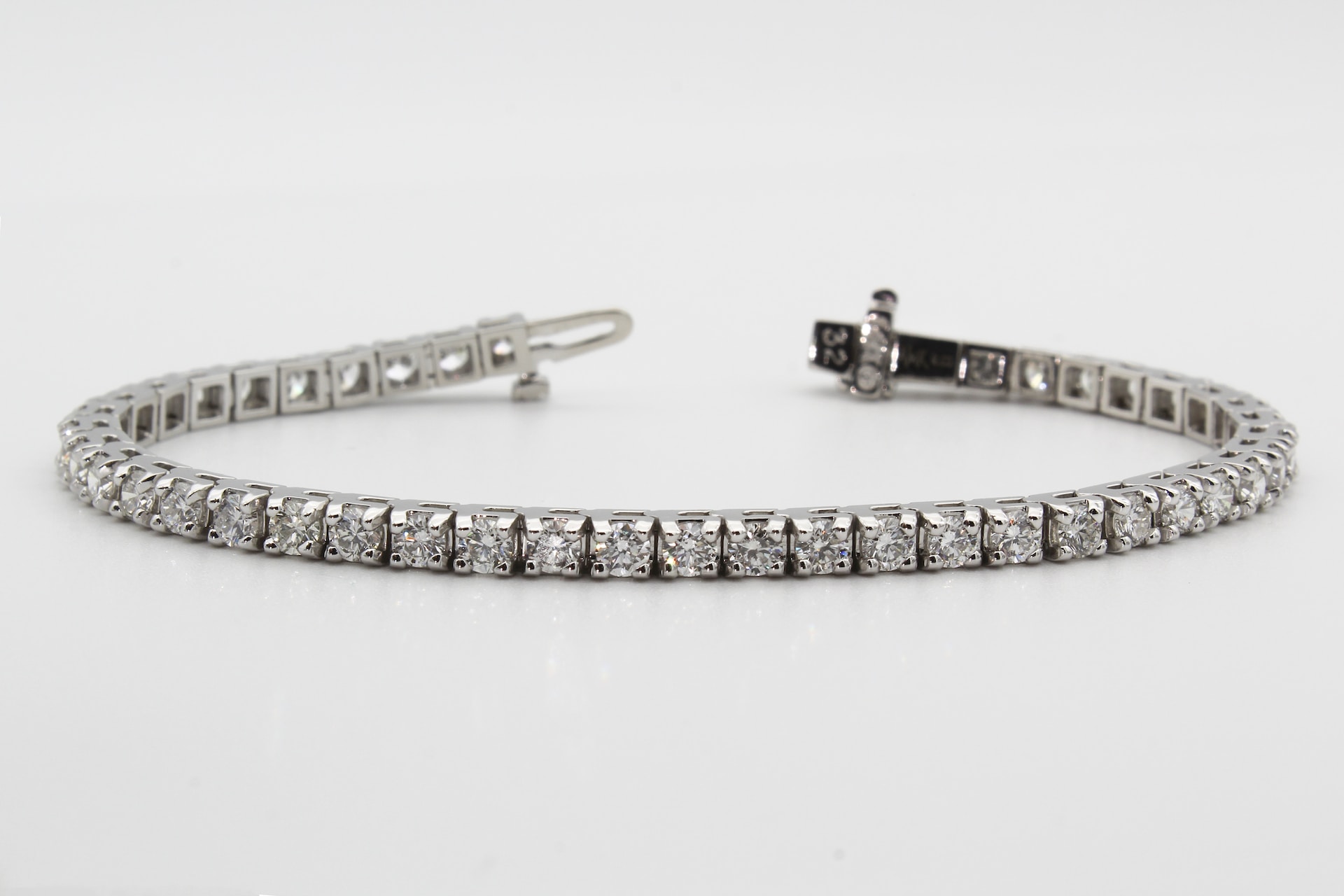 diamond and white gold tennis bracelet on a gray background